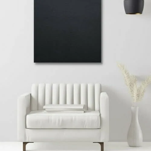 A white chair and a black square on a white wall