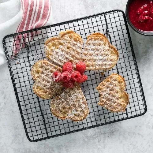 A heart shaped waffles with raspberries on top
